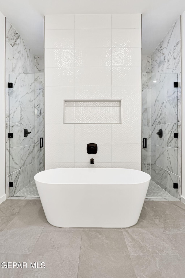 bathroom featuring a marble finish shower, marble finish floor, a freestanding bath, and tile walls