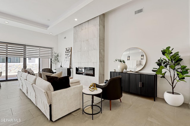 living room featuring a tiled fireplace, a high ceiling, recessed lighting, and visible vents