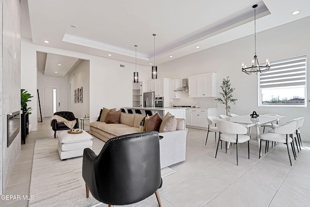 living area with recessed lighting, a tray ceiling, a notable chandelier, and a towering ceiling