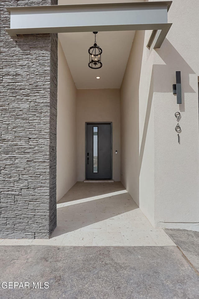 view of exterior entry with elevator, stone siding, and stucco siding