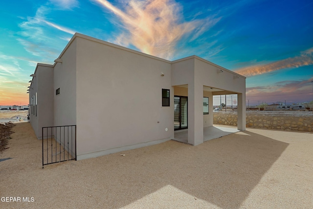 back of house at dusk with a patio area and stucco siding