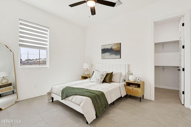 bedroom featuring a walk in closet, visible vents, a closet, light tile patterned flooring, and baseboards