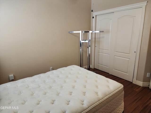 bedroom featuring dark wood-style floors, a closet, and baseboards