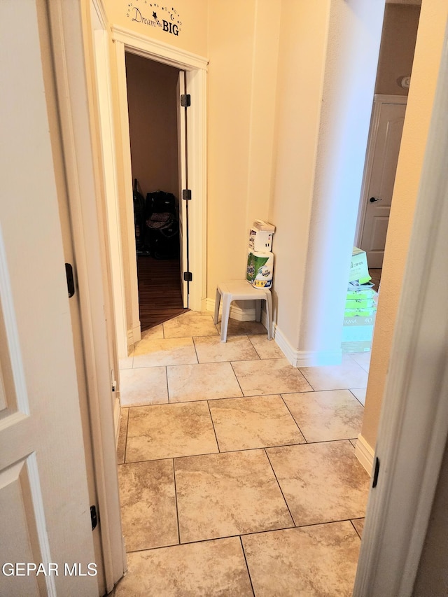 corridor with tile patterned flooring and baseboards