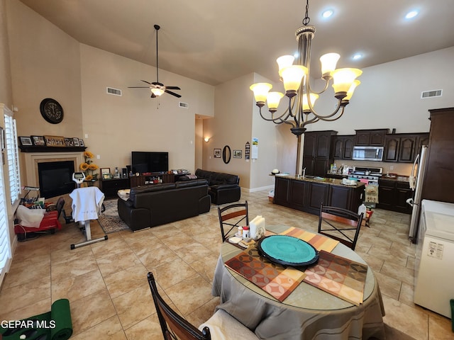 dining area with a high ceiling, ceiling fan with notable chandelier, and visible vents