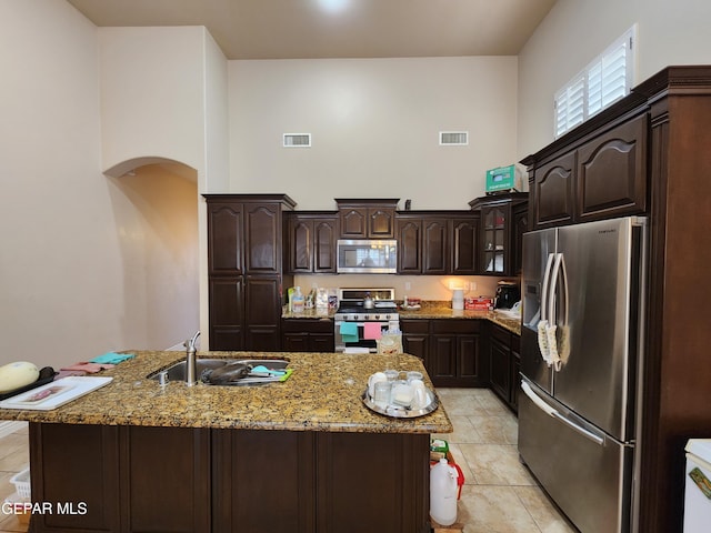 kitchen with light stone counters, visible vents, a high ceiling, arched walkways, and stainless steel appliances