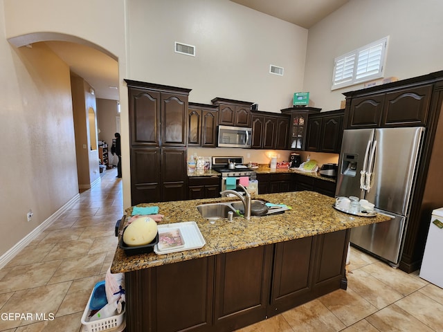 kitchen with visible vents, a high ceiling, arched walkways, stainless steel appliances, and a sink