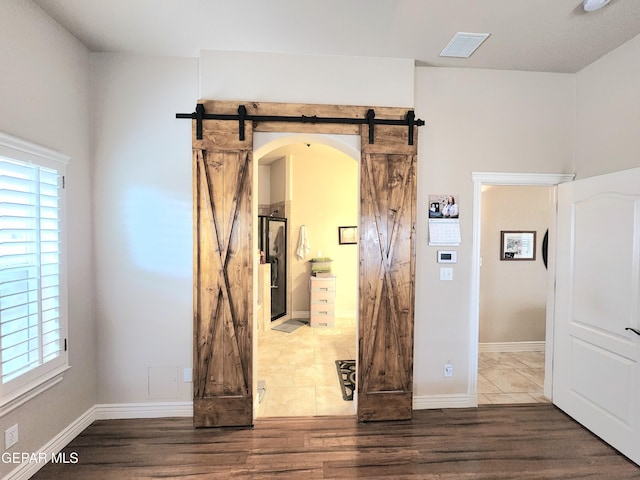 interior space with a barn door, arched walkways, plenty of natural light, and visible vents