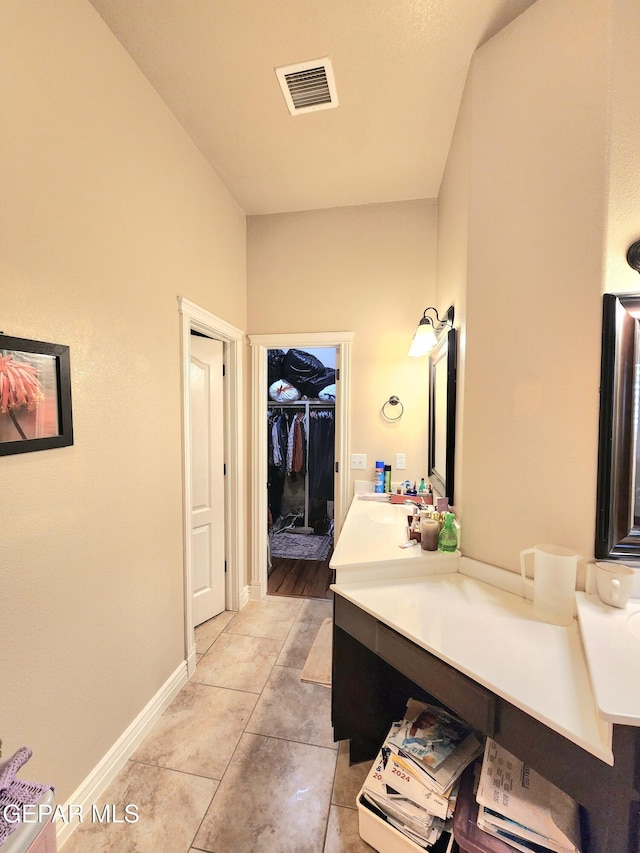 bathroom featuring vanity, baseboards, visible vents, a spacious closet, and tile patterned floors