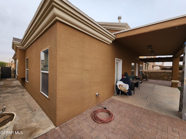 view of side of property with stucco siding and a patio