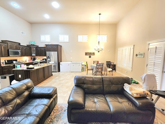 living area featuring light tile patterned floors, visible vents, an inviting chandelier, and a towering ceiling