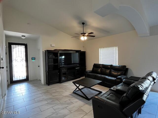 living room with arched walkways, ceiling fan, and vaulted ceiling