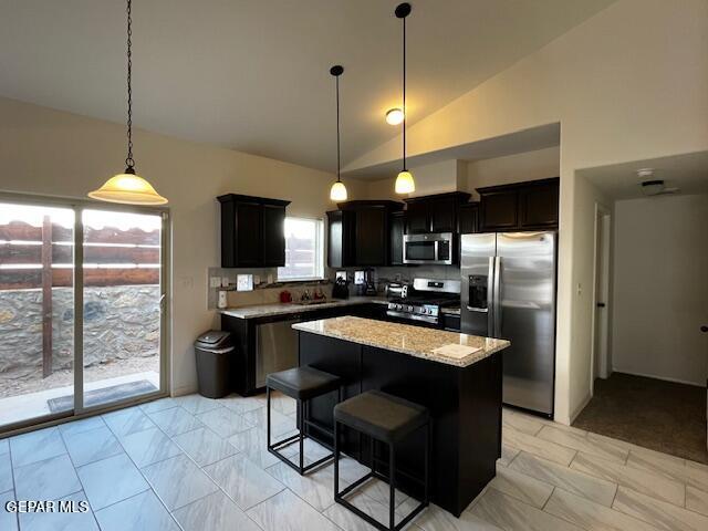 kitchen featuring hanging light fixtures, lofted ceiling, appliances with stainless steel finishes, and a center island