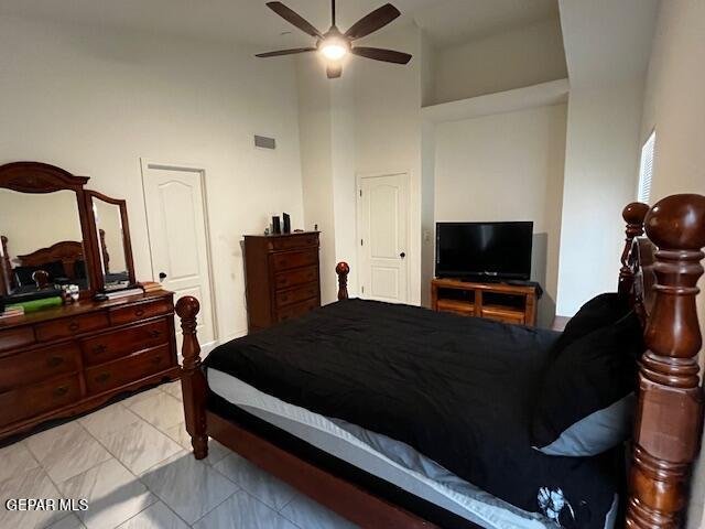 bedroom featuring visible vents, a high ceiling, and ceiling fan