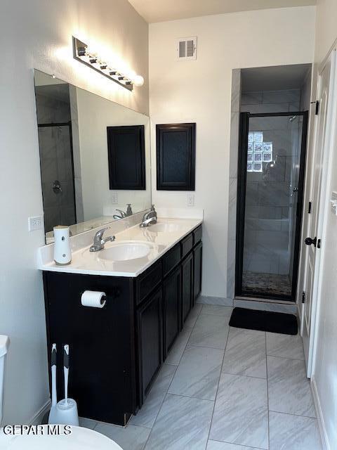 full bath featuring double vanity, a shower stall, marble finish floor, and a sink