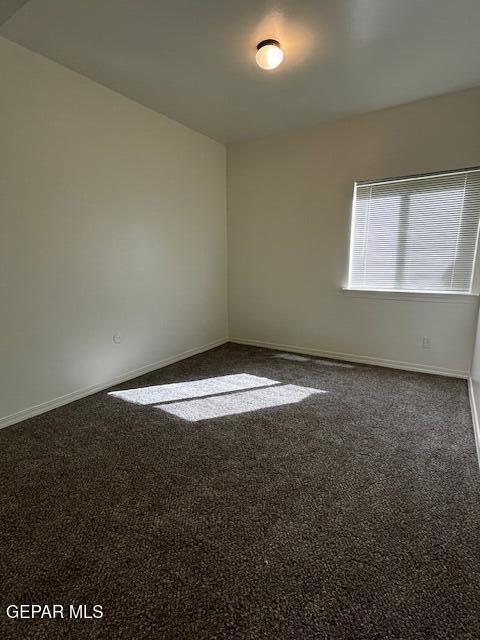 empty room with baseboards and dark carpet