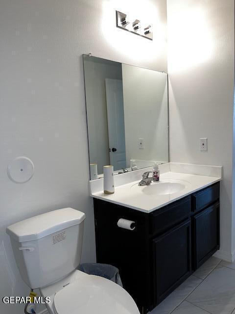 bathroom featuring toilet, marble finish floor, and vanity