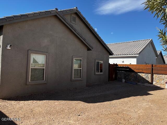 view of side of home featuring stucco siding and fence