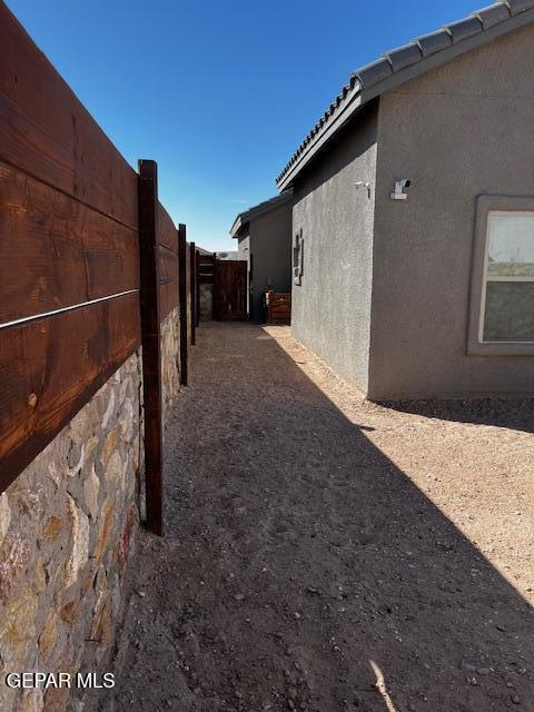 view of side of property with stucco siding and fence