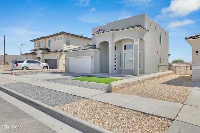 view of front of home featuring a tile roof, a garage, driveway, and stucco siding