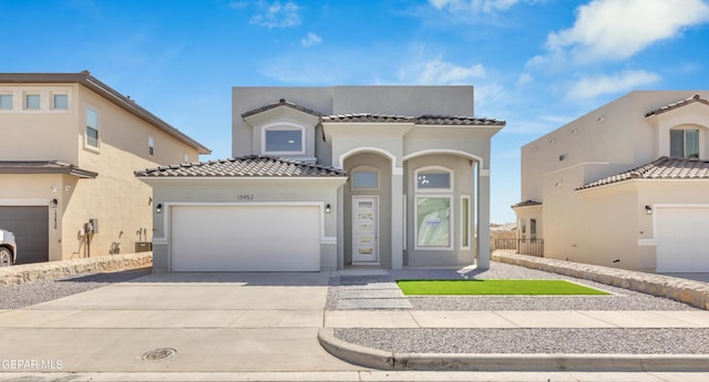 mediterranean / spanish house featuring concrete driveway, a tiled roof, a garage, and stucco siding