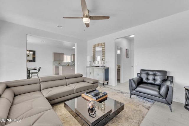 living area with a ceiling fan, visible vents, and light wood finished floors