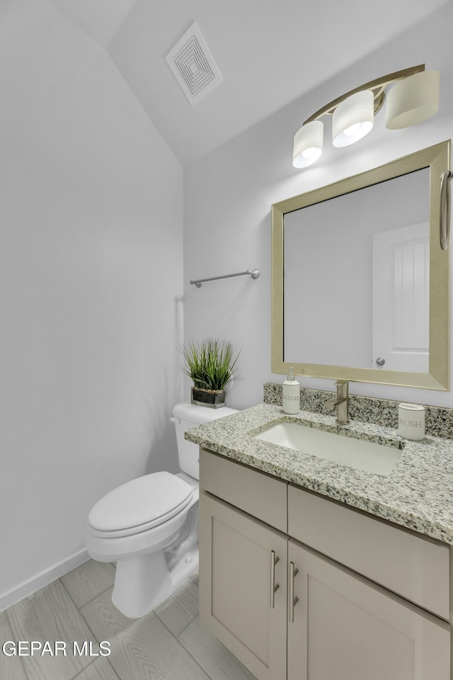 bathroom with visible vents, toilet, vanity, and lofted ceiling