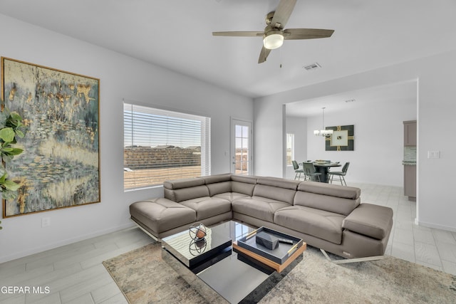 living room featuring ceiling fan with notable chandelier, visible vents, and baseboards