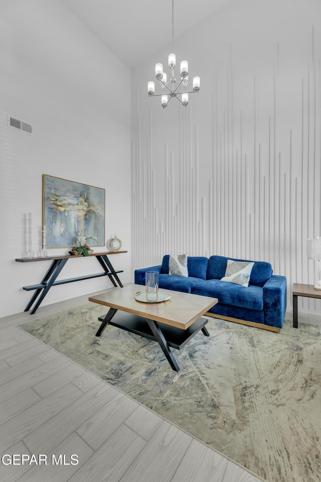 living area featuring visible vents, wood finished floors, and a chandelier