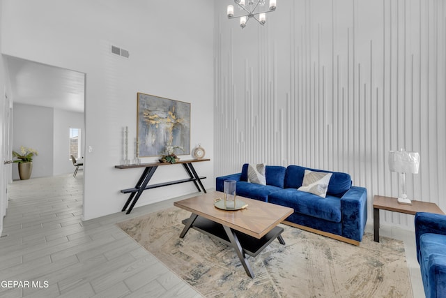 living room with visible vents, an inviting chandelier, and wood finished floors