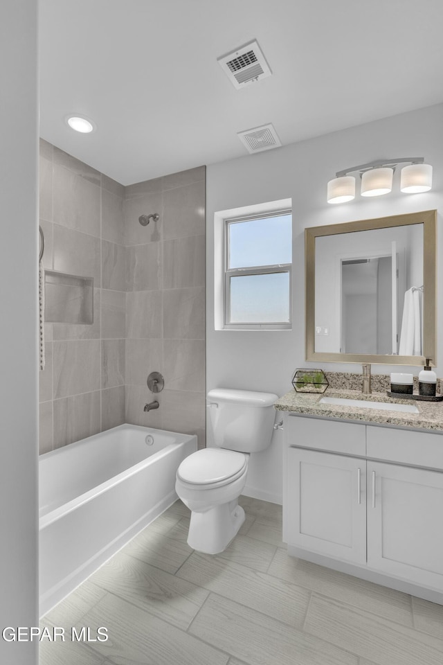 bathroom with vanity, toilet, visible vents, and shower / washtub combination