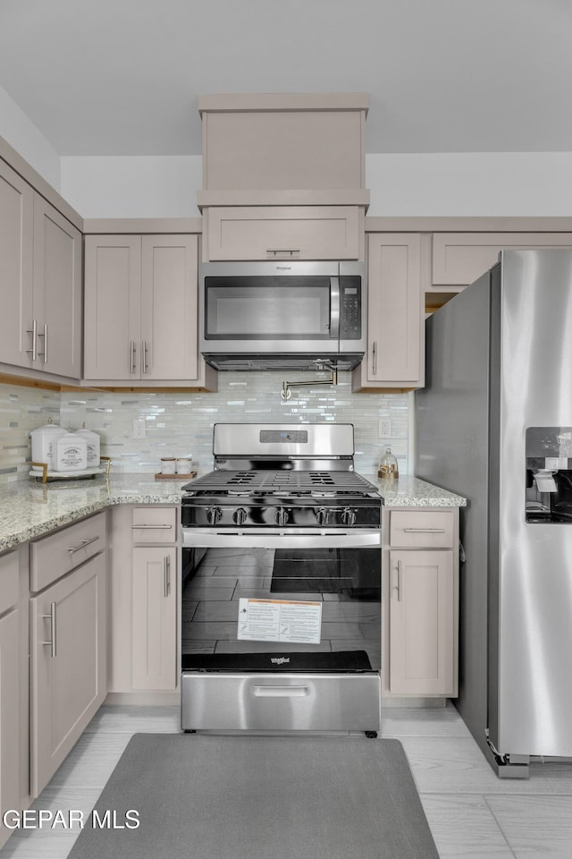 kitchen with stainless steel appliances, light stone countertops, and tasteful backsplash