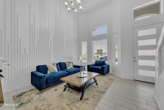 living area with an inviting chandelier, a high ceiling, wood finished floors, and baseboards