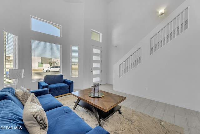 living area featuring baseboards, a towering ceiling, and wood finished floors