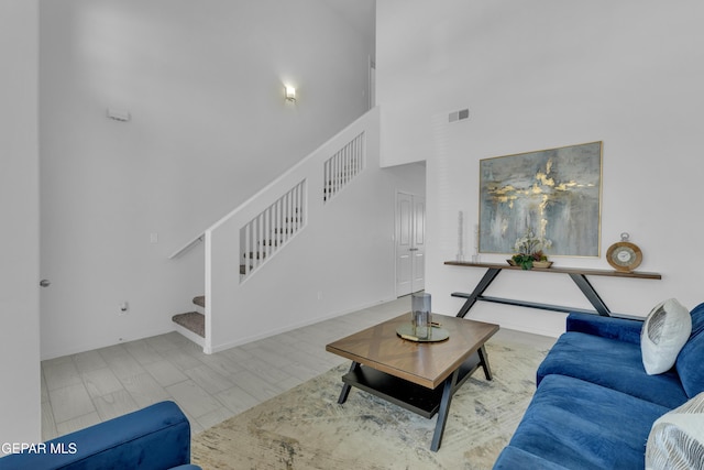 living area with stairs, a high ceiling, wood finished floors, and visible vents