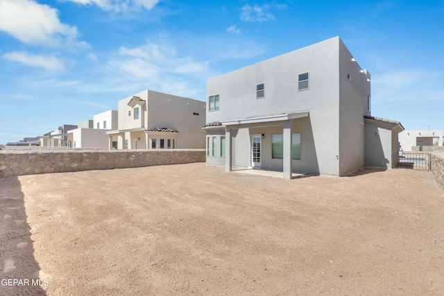 back of property featuring a patio area, a residential view, stucco siding, and fence