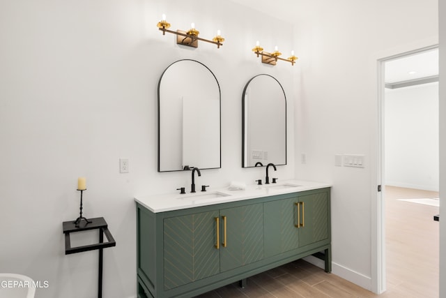 bathroom with a sink, baseboards, wood finished floors, and double vanity