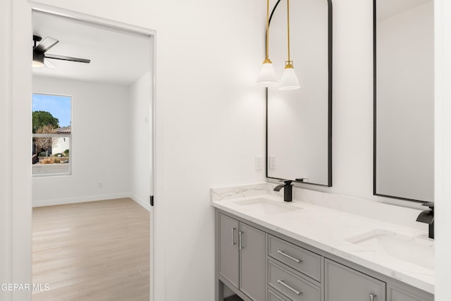 bathroom with double vanity, wood finished floors, ceiling fan, and a sink