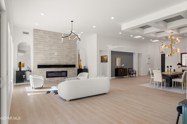 living room featuring light wood-type flooring, visible vents, a notable chandelier, a high end fireplace, and recessed lighting