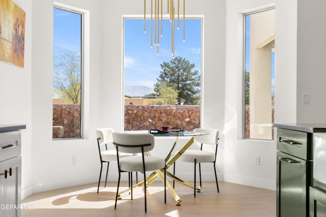 dining area with a wealth of natural light, baseboards, and light wood finished floors