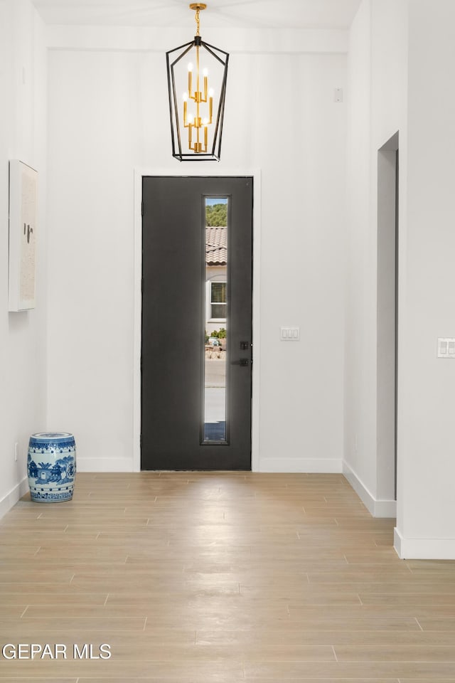 foyer with baseboards, a notable chandelier, and wood finished floors