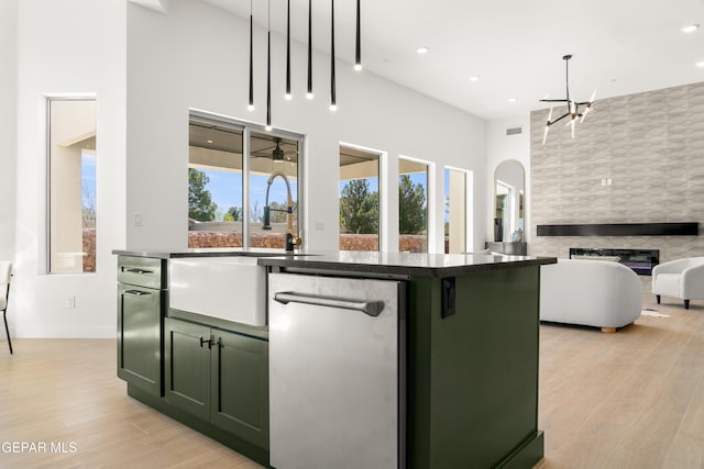 kitchen featuring green cabinets, a tiled fireplace, open floor plan, light wood-type flooring, and stainless steel dishwasher