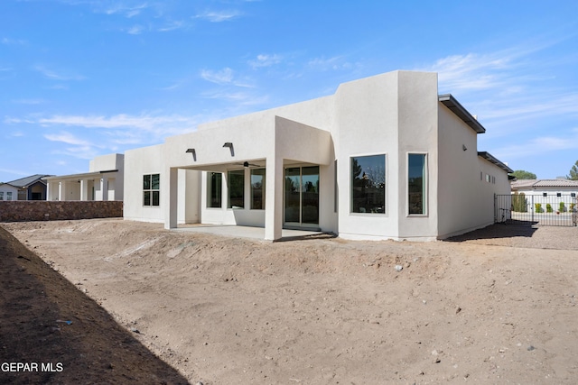 rear view of house featuring a ceiling fan, a patio area, fence, and stucco siding