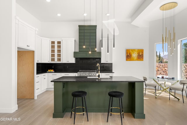 kitchen with dark countertops, decorative backsplash, white cabinets, and light wood-type flooring