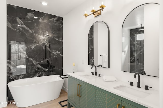 bathroom with a marble finish shower, a soaking tub, double vanity, and a sink