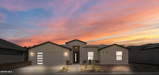 view of front of property featuring stucco siding, concrete driveway, and an attached garage