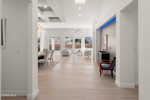 corridor with recessed lighting, baseboards, an inviting chandelier, and light wood finished floors