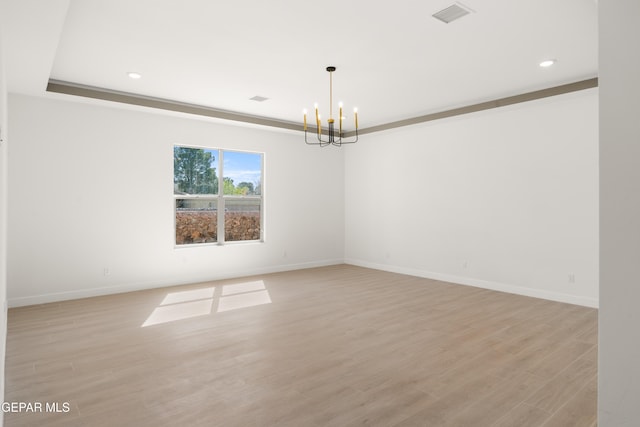 empty room with visible vents, baseboards, an inviting chandelier, and light wood-style flooring