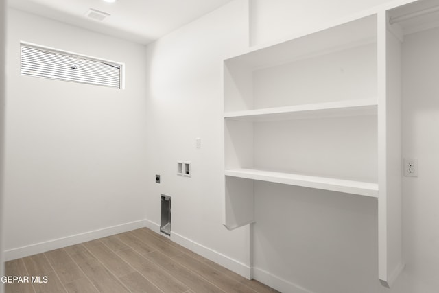 clothes washing area featuring electric dryer hookup, light wood-type flooring, baseboards, hookup for a washing machine, and laundry area