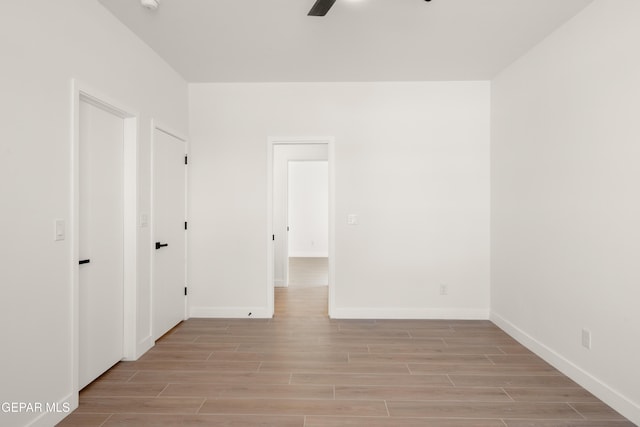 empty room featuring a ceiling fan, baseboards, and wood tiled floor